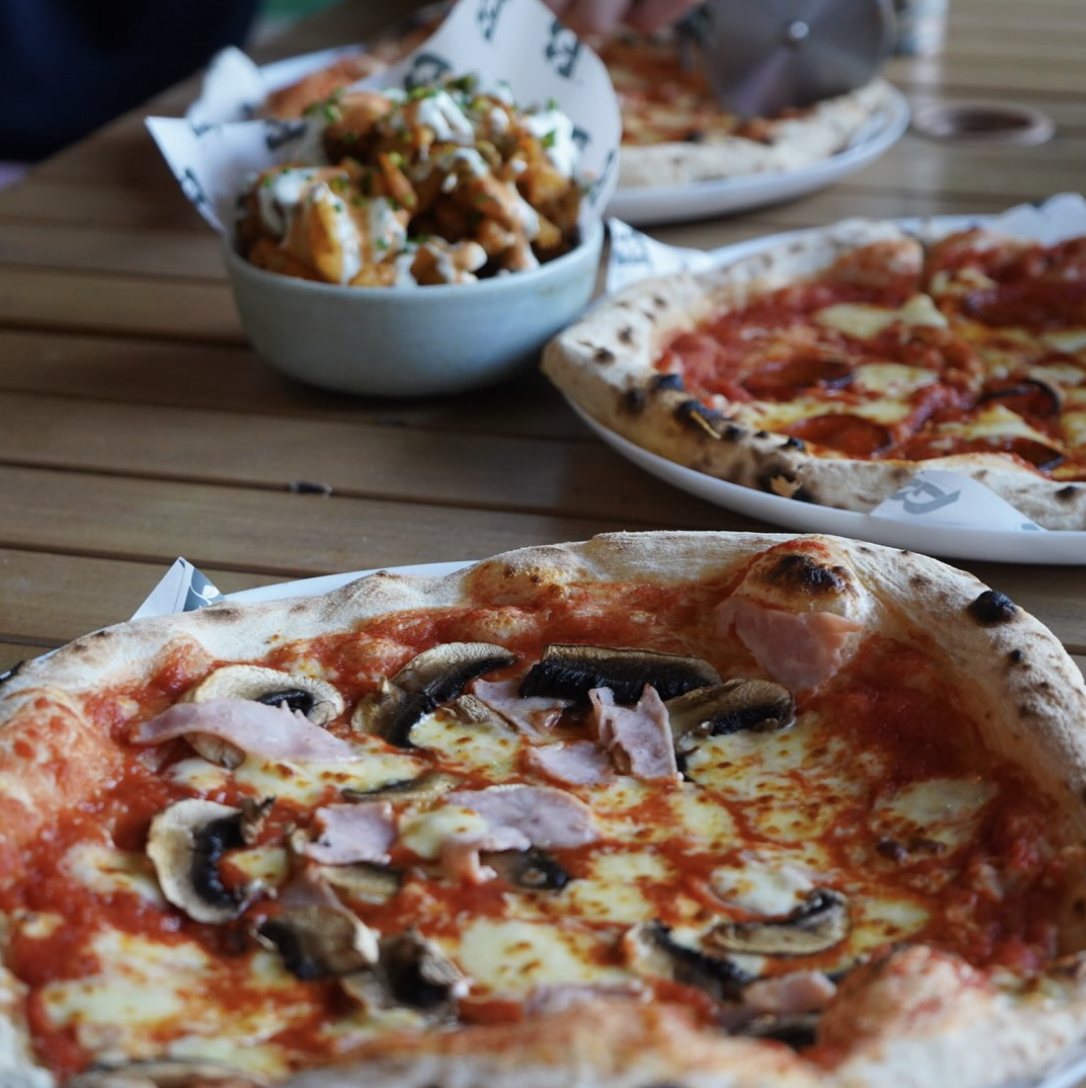 Ham and mushroom Neapolitan pizza on a wooden table